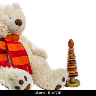 Des ours en peluche avec écharpe rouge et anneau en bois agrafeuse sur fond blanc. Old vintage toys. Banque D'Images