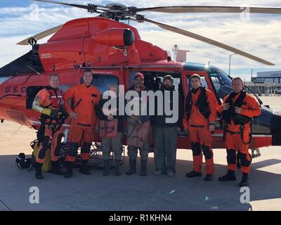 Un hélicoptère de la Garde côtière d'équipage de la station d'Air Atlantic City pose pour une photo aux côtés des trois plaisanciers ils ont sauvé d'un esquif de terre près de Egg Island Point, New Jersey, 17 octobre 2018. Les plaisanciers s'est échoué en raison de la marée basse, et ont été sauvés lorsque la marée haute n'a pas re-float leur navire. Banque D'Images