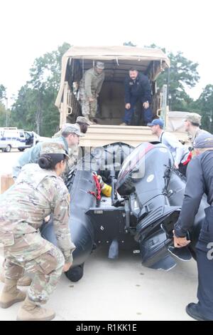 Les premiers intervenants d'urgence et la Garde nationale du Texas travaillent ensemble pour soulever un bateau de sauvetage à l'eau sur un véhicule de soutien de la Garde nationale dans la région de Huntsville, Texas, le 18 octobre 2018. Gardes du Texas ont travaillé avec les premiers intervenants d'urgence pour aider les Texans dans le besoin au cours de graves inondations. Banque D'Images