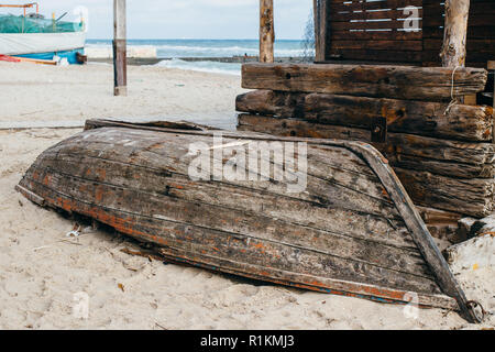 Old rusty bateau de pêche en bois portant sur la côte de sable renversé près de mer à jour. Banque D'Images