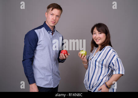 La diversité ethnique en multi couple holding studio pomme fruit vert et rouge Banque D'Images