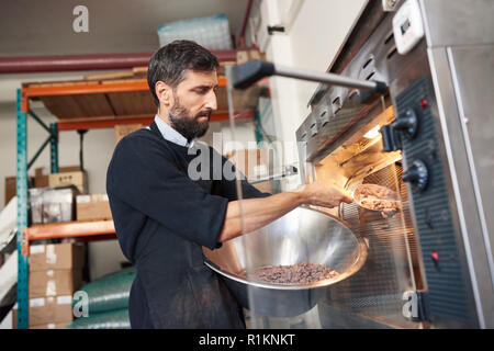 Les fèves de cacao torréfaction travailleur dans une usine de fabrication de chocolat Banque D'Images