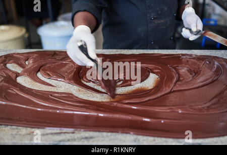 Worker mixing chocolat avec spatules sur une table d'usine Banque D'Images