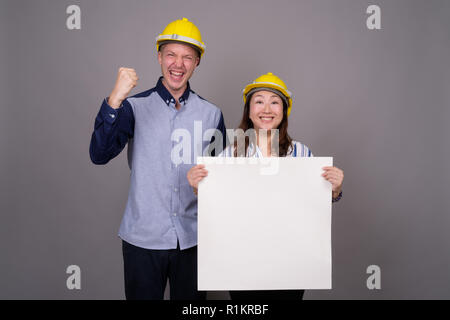 Businessman et mature Asian businesswoman wearing hardhat Banque D'Images