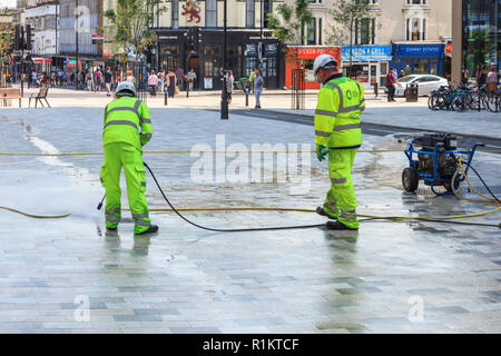 Les nettoyeurs de rue avec tuyaux à pression dans le navigateur 'Carré', retrait chewing-gums sur le nouveau centre piétonnier d'Archway, au nord de Londres, UK Banque D'Images
