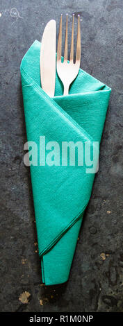 Fourchette et couteau enveloppé dans une serviette de papier vert sur une surface en marbre ou granit sombre Banque D'Images