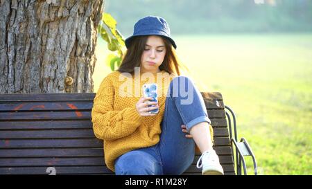 Portrait d'une belle adolescente de 14 ans aux yeux bleus qui écrit des messages texte SMS vers le téléphone mobile chatter avec réseau social Banque D'Images