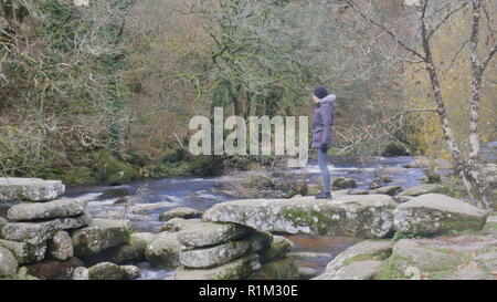 Baby Boomer femelle magnifique se dresse sur les ruines d'un claquoir pont sur la rivière Dart à Dartmeet Banque D'Images