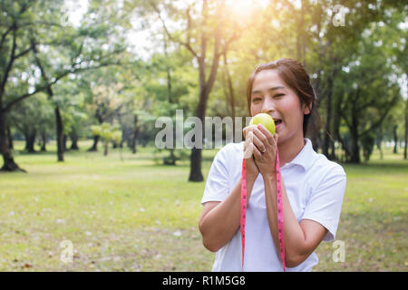 Sport woman holding green apple et de mesure Banque D'Images