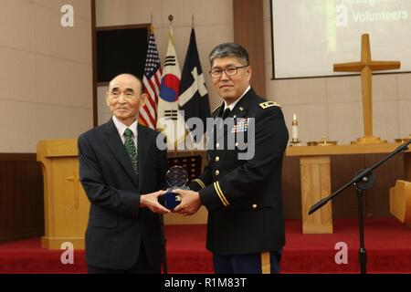 CAMP RED CLOUD, République de Corée - Aumônier (Lt. Le colonel) a gagné, Sang Joon, Séoul, indigènes de l'armée américaine et aumônier du commandement de Yongsan Garrison, présente M. Kim, Ki Ye, avec une plaque en reconnaissance de plus de 32 ans de service bénévole pour Chapelle Guerrier d'organiste pendant la cérémonie de mise hors service le 21 octobre. M. Kim croit qu'à travers la musique et la louange, les soldats américains et coréens peuvent réduire l'écart dans les différences linguistiques. Banque D'Images