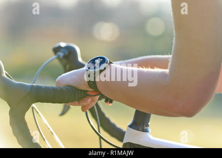 Woman riding a bike et l'utilisation de moniteur de fréquence cardiaque pour smartwatch Banque D'Images