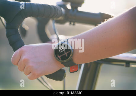 Woman riding a bike et l'utilisation de moniteur de fréquence cardiaque pour smartwatch Banque D'Images