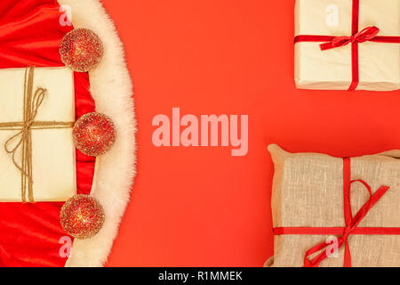 Close-up of Santa's clothes, décoration paillettes boules et cadeaux de Noël. sur fond rouge. Copie vierge vide de l'espace pour le texte. Banque D'Images