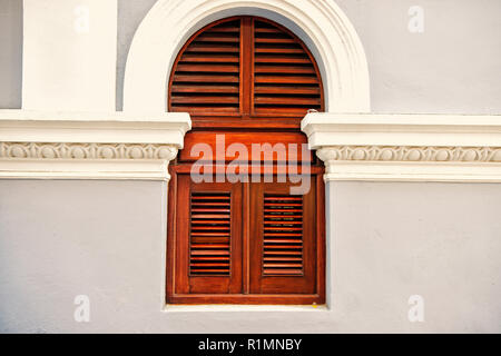 Fenêtre avec des volets en bois sur fond de mur gris à San Juan, Porto Rico. Maison avec façade crépi. La symétrie et la géométrie urbaine concept. Construction et rénovation. Banque D'Images