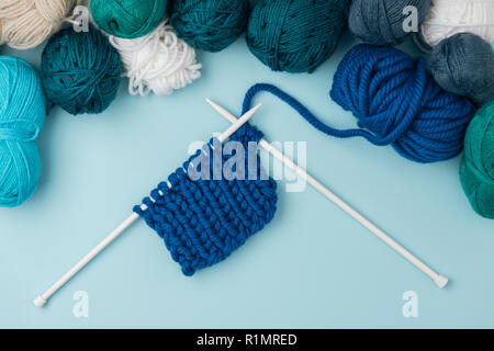 Vue de dessus du fil blanc et clews a organisé des aiguilles à tricoter sur fond bleu Banque D'Images