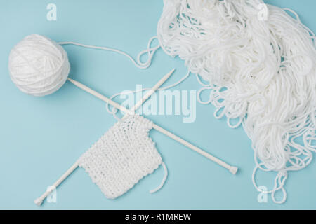 Vue de dessus du fil blanc et des aiguilles à tricoter sur fond rose Banque D'Images