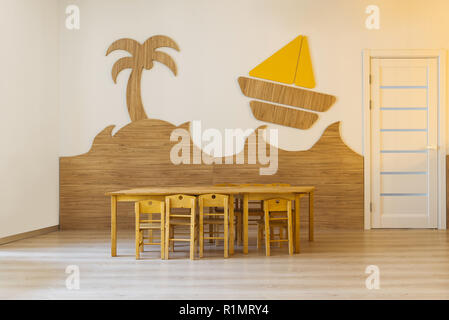 Chambre confortable avec table et chaises en bois et des éléments décoratifs en mur dans la maternelle moderne Banque D'Images