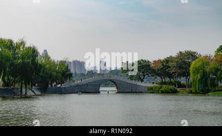 Passerelle de pierre blanche dans un jardin chinois lacated entre le bâtiment moderne. Wuhan, Hubei en Chine. Banque D'Images