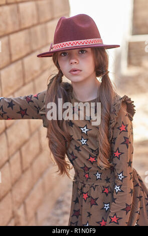 Jeune fille portant un chapeau de bourgogne et une robe marron avec étoiles looking at camera Banque D'Images