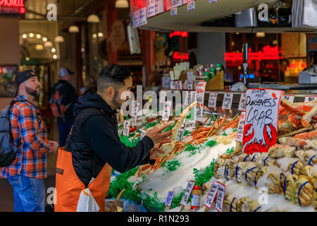 Seattle, États-Unis - Novembre 08, 2018 : poissonnier mettant les pattes de crabe frais sur la glace pour la vente à un décrochage à Pike Place Market avec un client dans le Banque D'Images