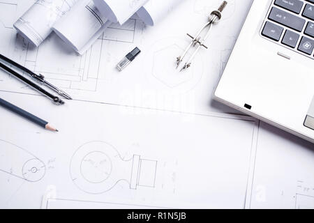 Un cahier, un crayon, un compas et des rouleaux avec des dessins sur le tableau de l'architecte Banque D'Images