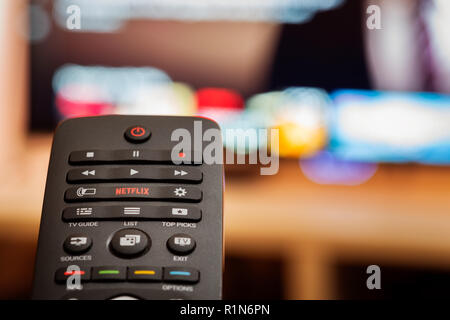 TV Remote avec bouton Netflix dédié en face de Smart TV de flou artistique Banque D'Images