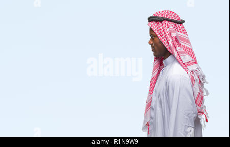 Jeune arabe african man wearing keffieh traditionnel sur fond isolé à côté de beauté, posent avec profil visage naturel avec certain sm Banque D'Images