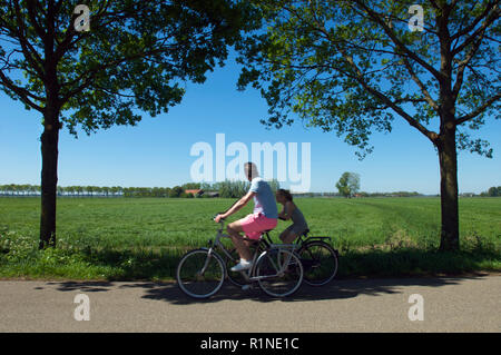 Père et fille sur une promenade en vélo sur une journée d'été avec vue sur les terres agricoles, les Pays-Bas Banque D'Images