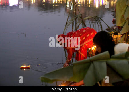 Un dévot népalais vus offrant des prières pour le coucher de soleil dans l'eau pendant l'Chhath Puja festival. Le Chhath Festival, également connu sous le nom de Surya Pooja, ou le culte du soleil, est observée dans les régions de l'Inde et le Népal comme dévots rendent hommage au soleil et l'eau des dieux. Banque D'Images