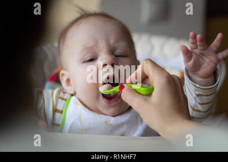 Le début de l'alimentation du bébé à partir de la cuillère. Maman Bébé aliments aliments hachés homogénéisé avec une cuillère. garde des enfants. de vie. Banque D'Images