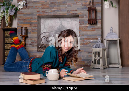 Portrait de superbe brunette woman reading book élégante près de la cheminée. L'analyse de l'intérieur.concept.L'enseignement de la lecture des livres de l'automne automne confortable.l'humeur. Temps d'automne.atmosphère confortable. Banque D'Images