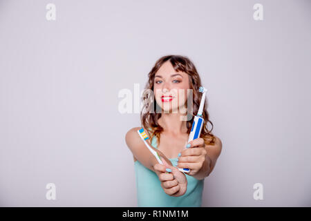 Brosse à dents électrique et traditionnelles.Hygiène de la cavité orale. Une belle jeune femme choisit entre une bouilloire et une brosse à dents simple.Happy smiling woman le brossage des dents avec une brosse à dents.Copy space Banque D'Images