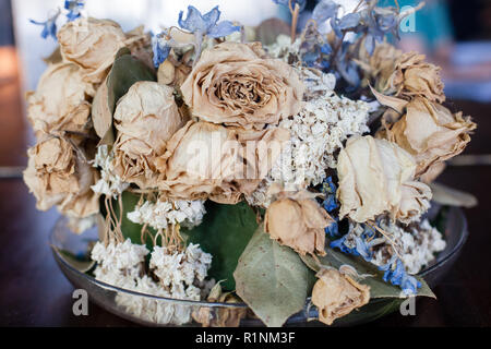 Une vue rapprochée d'un arrangement de fleurs séchées de couleur pâle, roses et autres fleurs dans un bol en verre. Banque D'Images