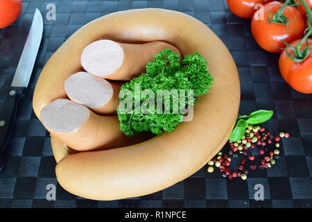 Lyoner est une saucisse fines sur un napperon noir. Lyoner un Wurst-Delikatessen auf einem schwarzen Tischset. Banque D'Images