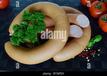 Lyoner est une saucisse fines sur un napperon noir. Lyoner un Wurst-Delikatessen auf einem schwarzen Tischset. Banque D'Images