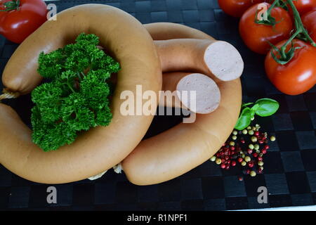 Lyoner est une saucisse fines sur un napperon noir. Lyoner un Wurst-Delikatessen auf einem schwarzen Tischset. Banque D'Images