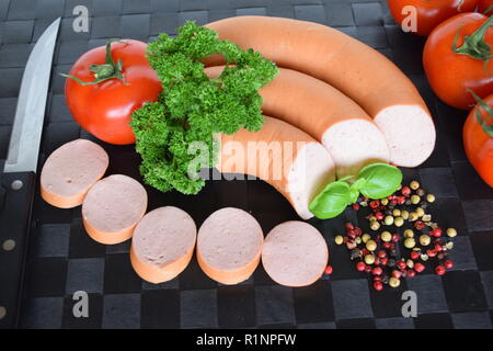 Lyoner est une saucisse fines sur un napperon noir. Lyoner un Wurst-Delikatessen auf einem schwarzen Tischset. Banque D'Images