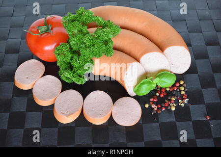 Lyoner est une saucisse fines sur un napperon noir. Lyoner un Wurst-Delikatessen auf einem schwarzen Tischset. Banque D'Images