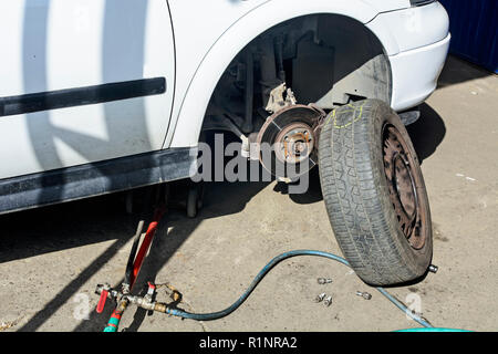 Changer les roues de la voiture qui se trouve en face d'un atelier. Banque D'Images