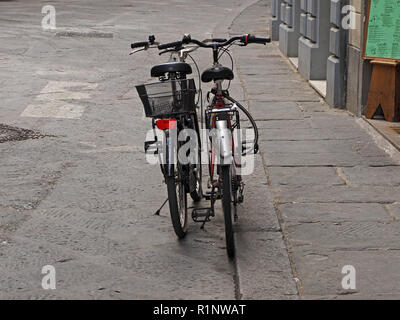 Deux cycles garé sur stands côte à côte dans la rue déserte à Florence, Toscane, Italie Banque D'Images
