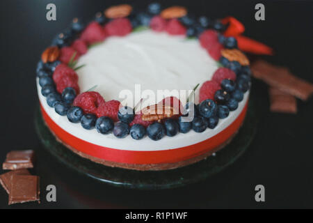 Framboises bleuets gâteau artisanal aux fruits rouges, gâteau au fromage sur un fond noir, Banque D'Images