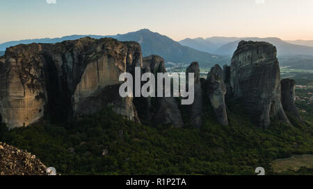 D'énormes rochers de monastères et le coucher du soleil derrière les montagnes lointaines de météores, Thessalie, Grèce Banque D'Images