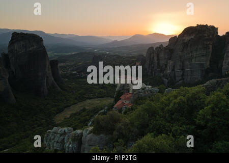 D'énormes rochers de monastères et le coucher du soleil derrière les montagnes lointaines de météores, Thessalie, Grèce Banque D'Images