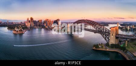 Ciel coloré sur la ville de Sydney CBD hautes tours au lever du soleil autour de la baie de Sydney et le Sydney Harbour Bridge en antenne élevée panorama. Banque D'Images