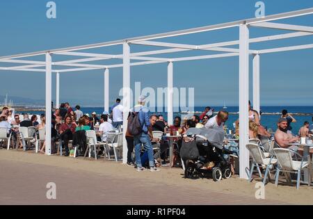 Les gens s'assoient dans un bar sur la plage de Barceloneta à Barcelone, Espagne le 17 avril 2018. Banque D'Images