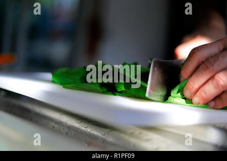 Les mains à couper des légumes dans la cuisine le matin Banque D'Images