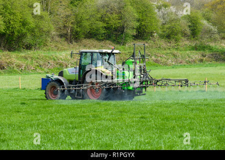 Agriculteur occupé au travail à la ferme, de la conduite du tracteur agricole de pulvérisation sur les terres agricoles, à l'aide de pulvérisateur à rampe pour distribuer des produits chimiques - North Yorkshire, Angleterre, Royaume-Uni. Banque D'Images