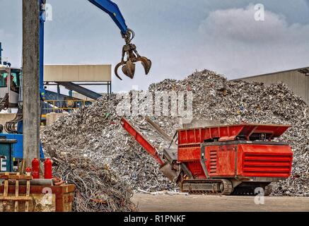 Un grab le levage de grandes quantités de déchets de métal dans une machine qui réduit le gaspillage de la sixe metal pour plus de processus de recyclage. Banque D'Images