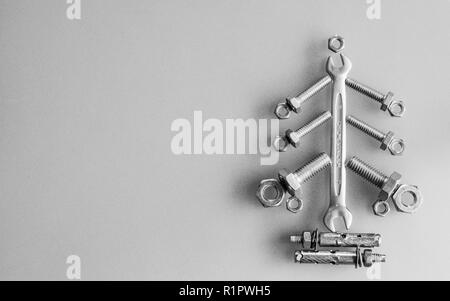 Clé dynamométrique, écrous et boulons décorée comme l'arbre de Noël sur un fond gris. Carte de vœux de Noël et Bonne année carte de souhaits concept. Vue supérieure de la wi Banque D'Images