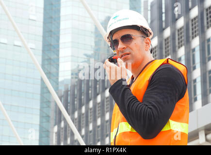 Porter un casque d'ingénieur et de l'utilisation de la communication radio pour contrôle de la tâche de travail at construction site Banque D'Images